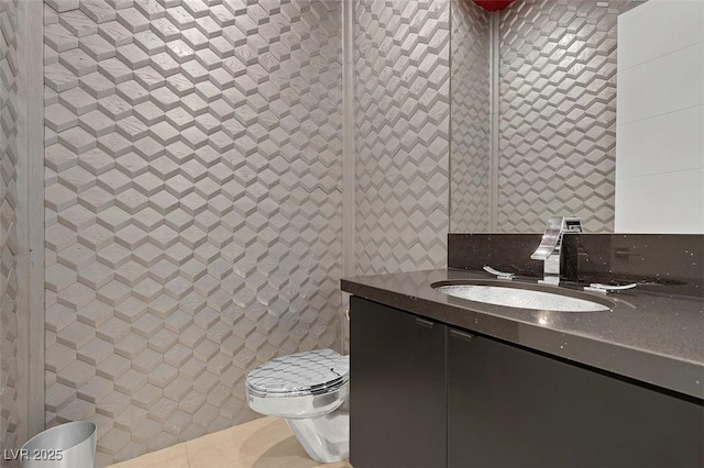 bathroom with vanity, toilet, and tile walls