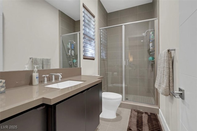 bathroom with tile patterned flooring, vanity, a shower with shower door, and toilet