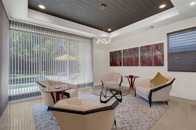 living area with a raised ceiling, light tile patterned floors, and wood ceiling