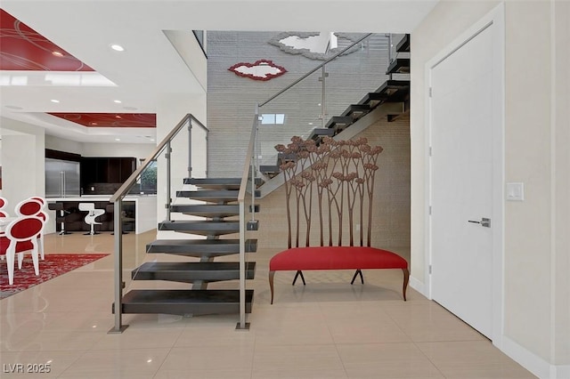 staircase featuring a tray ceiling and tile patterned flooring