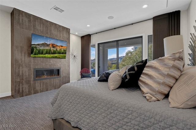 carpeted bedroom with a tile fireplace and access to exterior