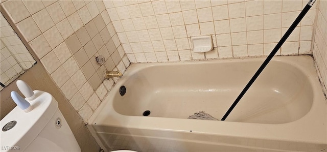 bathroom with a tub to relax in and toilet