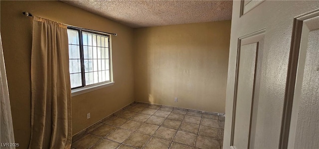 spare room with light tile patterned flooring and a textured ceiling