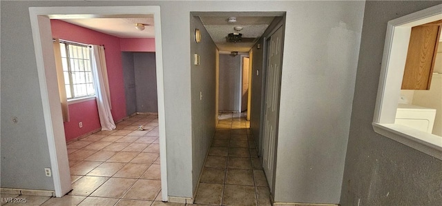 corridor with washer / clothes dryer and light tile patterned floors