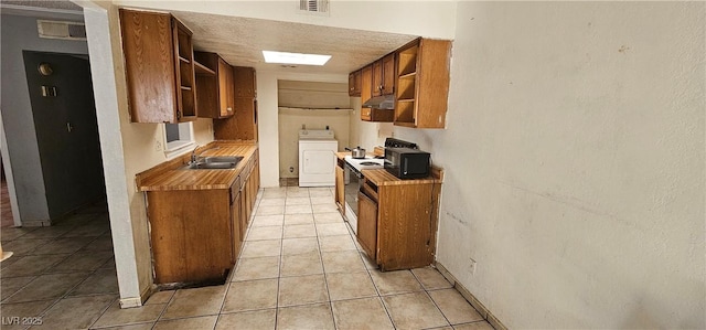 kitchen featuring light tile patterned flooring, white electric range, sink, a textured ceiling, and washer / clothes dryer