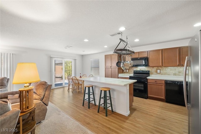 3924 E Garfield Dr, Pahrump, NV 89061 - kitchen featuring visible vents, black appliances, a breakfast bar, open floor plan, and light countertops