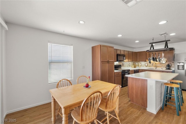 3924 E Garfield Dr, Pahrump, NV 89061 - kitchen with visible vents, black appliances, a sink, backsplash, and light wood-style floors