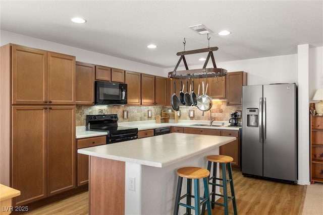 3924 E Garfield Dr, Pahrump, NV 89061 - kitchen featuring visible vents, light wood-type flooring, a sink, black appliances, and tasteful backsplash