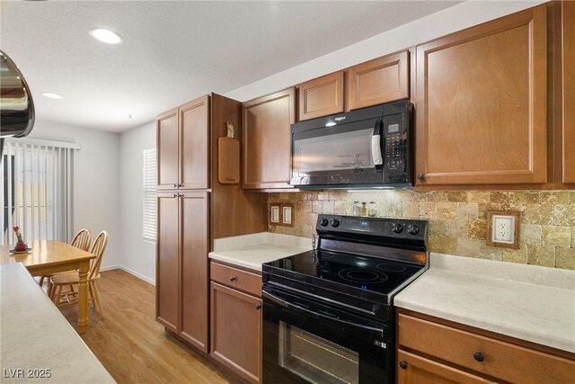 3924 E Garfield Dr, Pahrump, NV 89061 - kitchen with tasteful backsplash, light wood-style floors, black appliances, and light countertops