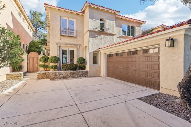 mediterranean / spanish house featuring driveway, a balcony, a garage, and a gate