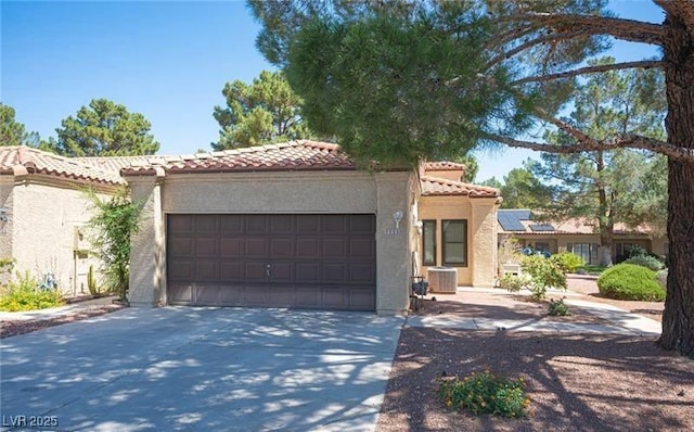 mediterranean / spanish-style home featuring a garage, central AC unit, and solar panels