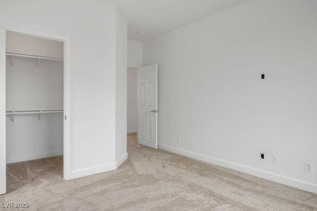 unfurnished bedroom with a walk in closet, a closet, and light carpet