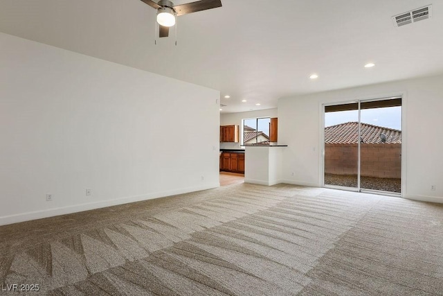 unfurnished living room featuring ceiling fan and light carpet