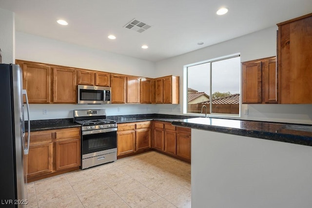 kitchen featuring stainless steel appliances, light tile patterned flooring, and dark stone countertops