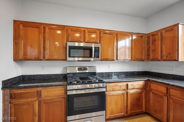 kitchen featuring dark stone countertops, light tile patterned floors, and appliances with stainless steel finishes