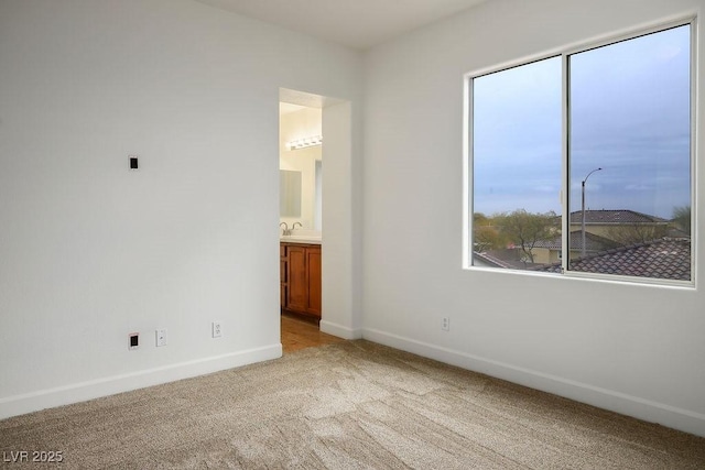 unfurnished bedroom with connected bathroom, sink, and light colored carpet