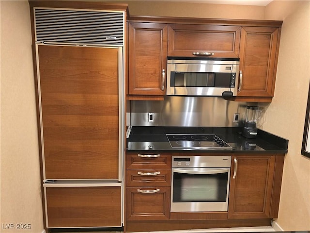135 E Harmon Ave Unit 2120, Las Vegas, NV 89109 - kitchen featuring dark countertops, appliances with stainless steel finishes, baseboards, and brown cabinetry