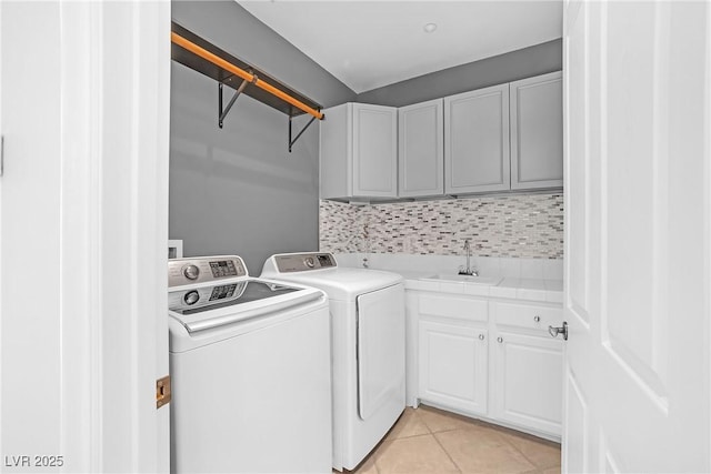 clothes washing area featuring cabinet space, washer and clothes dryer, a sink, and light tile patterned flooring