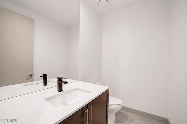 half bath featuring baseboards, vanity, toilet, and tile patterned floors