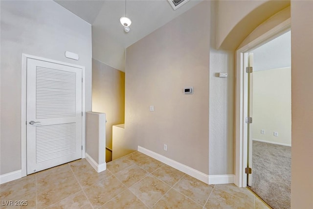 hallway with vaulted ceiling and light tile patterned floors