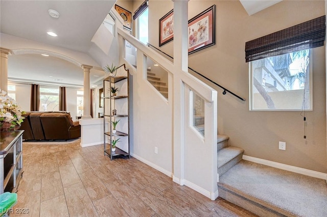 staircase featuring wood-type flooring and decorative columns