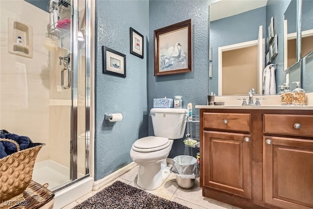 bathroom featuring vanity, toilet, tile patterned floors, and a shower with shower door