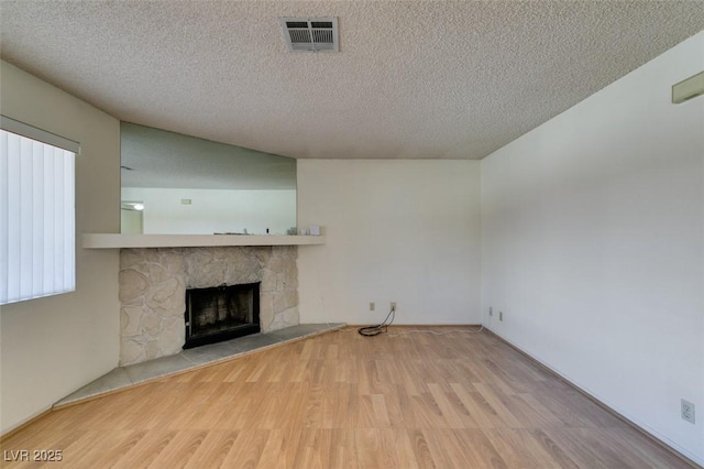 unfurnished living room featuring a fireplace, a textured ceiling, and light wood-type flooring