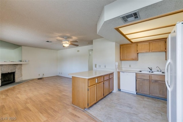 kitchen featuring a stone fireplace, sink, white appliances, kitchen peninsula, and ceiling fan