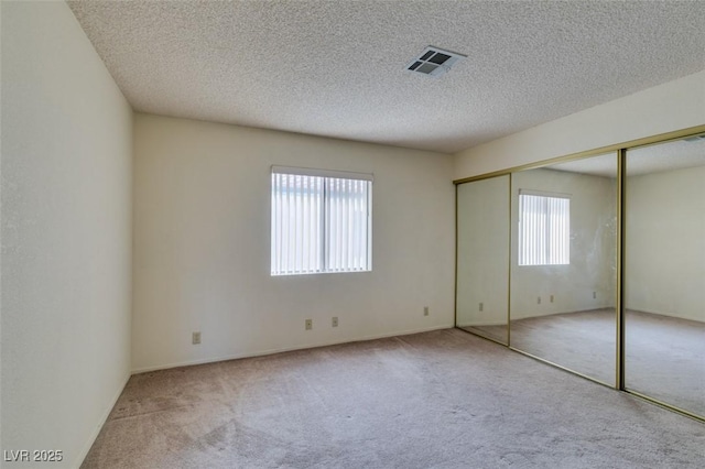 unfurnished bedroom featuring light colored carpet and a textured ceiling