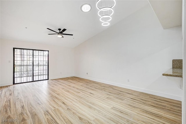 unfurnished room with lofted ceiling, ceiling fan with notable chandelier, and light wood-type flooring