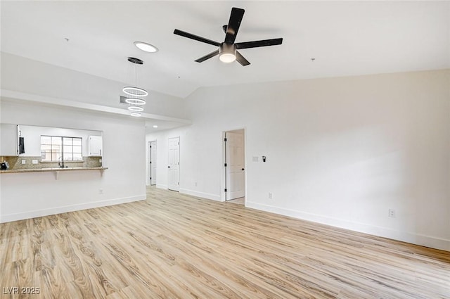 unfurnished living room featuring ceiling fan, sink, vaulted ceiling, and light hardwood / wood-style flooring