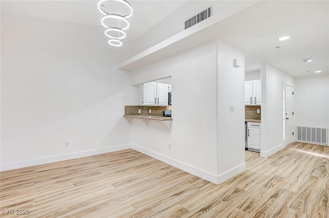 unfurnished living room with an inviting chandelier and light hardwood / wood-style floors