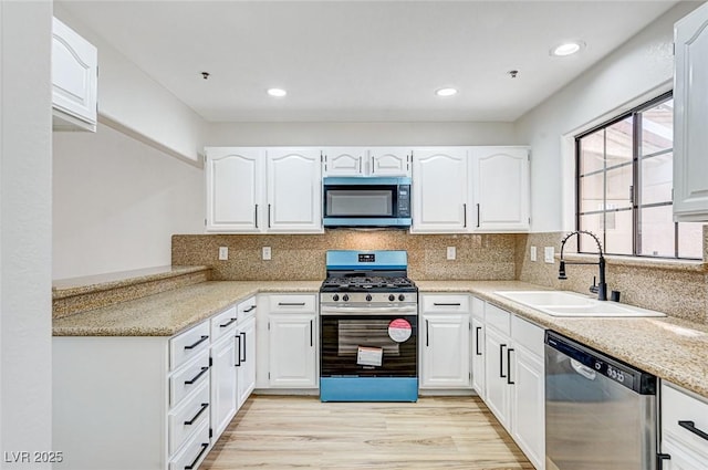 kitchen with sink, backsplash, stainless steel appliances, white cabinets, and light wood-type flooring