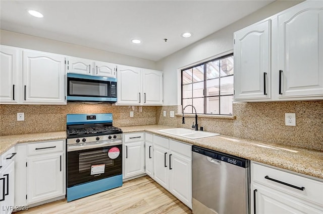 kitchen featuring white cabinetry, appliances with stainless steel finishes, sink, and light wood-type flooring