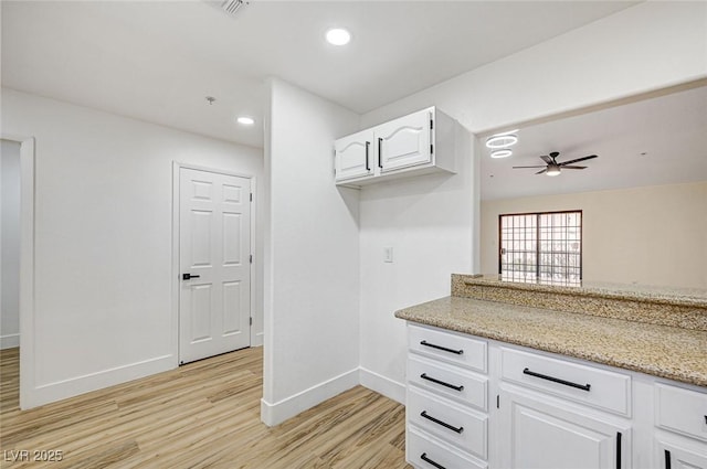 kitchen featuring white cabinetry, ceiling fan, light stone countertops, and light wood-type flooring