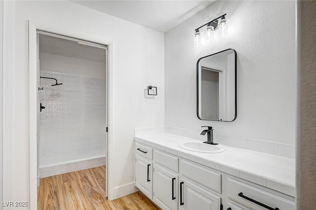 bathroom featuring hardwood / wood-style flooring, vanity, and tiled shower