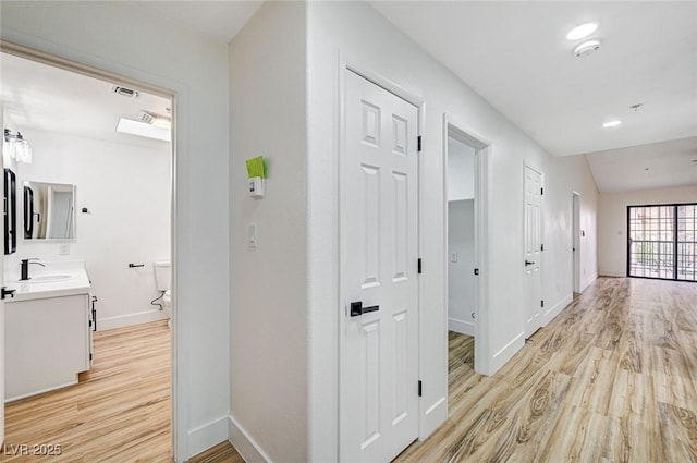 hallway featuring sink and light hardwood / wood-style floors