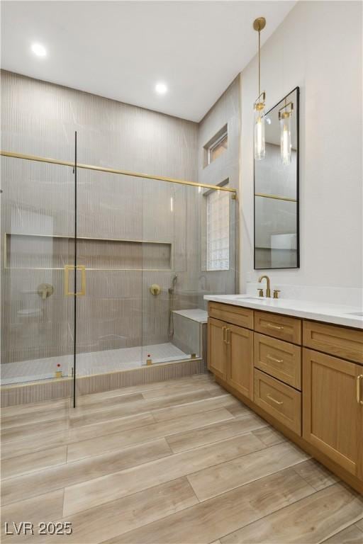 bathroom featuring vanity, a tile shower, and wood-type flooring