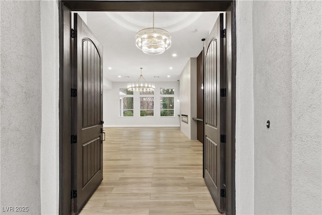 hallway featuring an inviting chandelier and light hardwood / wood-style flooring