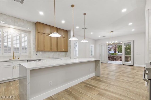 kitchen featuring sink, backsplash, a center island, white cabinets, and hanging light fixtures