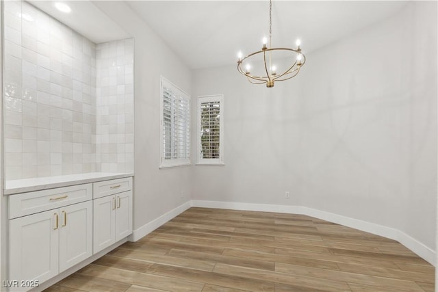 unfurnished dining area featuring light wood-type flooring and a chandelier