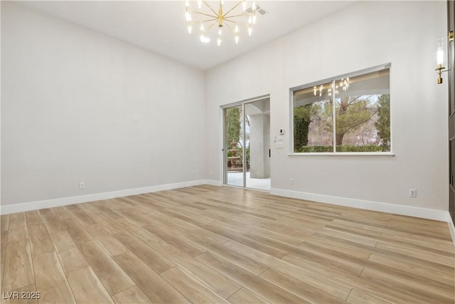 empty room featuring an inviting chandelier and light hardwood / wood-style flooring