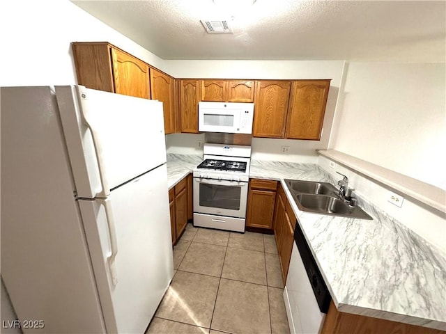 kitchen with sink, white appliances, a textured ceiling, and light tile patterned flooring