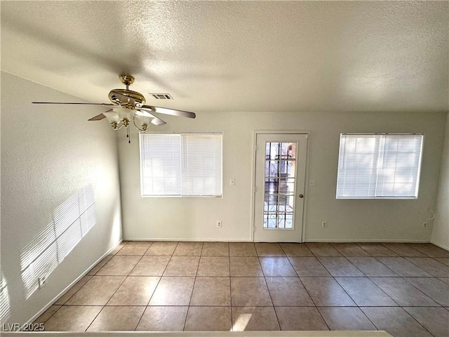 unfurnished room with ceiling fan, light tile patterned floors, and a textured ceiling