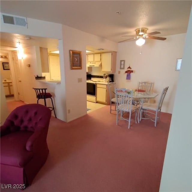 carpeted dining area with ceiling fan