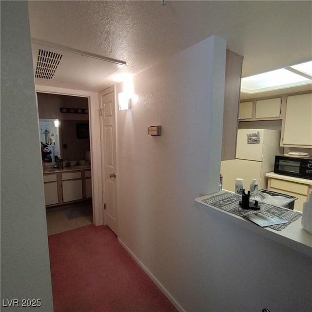 hallway with carpet flooring and a textured ceiling