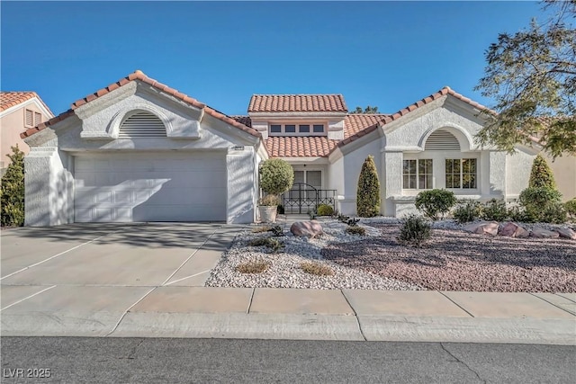 mediterranean / spanish-style home with concrete driveway, a tiled roof, a garage, and stucco siding