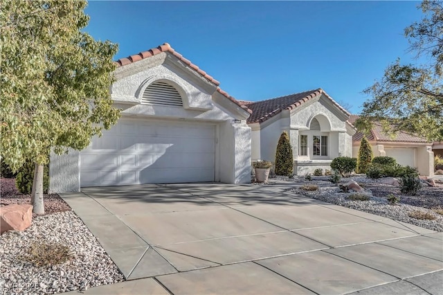 mediterranean / spanish-style house featuring stucco siding, a tiled roof, concrete driveway, and an attached garage