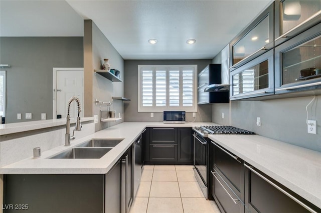 kitchen with sink, stainless steel gas range oven, light tile patterned floors, black dishwasher, and wall chimney range hood