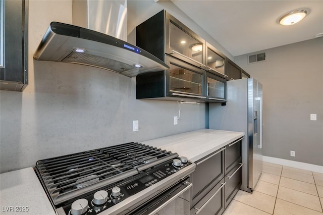 kitchen featuring light tile patterned flooring, stainless steel appliances, and wall chimney range hood